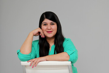 30-year-old Latin woman works sitting in an office chair and appears happy and satisfied with her professional growth