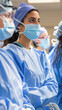 © sommersby - A group of surgeons wearing scrubs, masks, and caps observe a procedure in an operating room