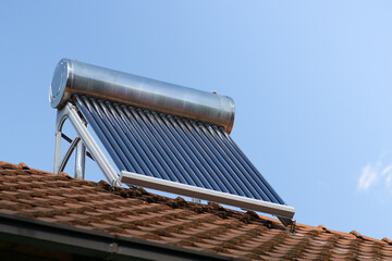 solar water heater on a roof top, solar water heating panel, blue sky in the background