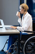 © Wavebreak Media - Working on laptop, woman in wheelchair drinking coffee at office desk