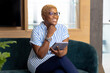 © Wavebreak Media - Smiling woman holding tablet, sitting on couch in modern office setting
