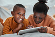 © peopleimages.com - Online, tablet and black children on bed for education, learning or skill development in bedroom. Digital, reading and kids with ebook subscription for information, literacy or knowledge in home