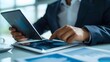 © Farid - A mature businessman standing in an office, using tablet.