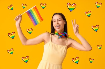 Wall Mural - Beautiful young woman with LGBT flag showing victory gesture on yellow background