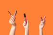 © Pixel-Shot - Female hands with mascara and lipsticks on orange background