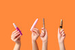 © Pixel-Shot - Female hands with mascaras on orange background