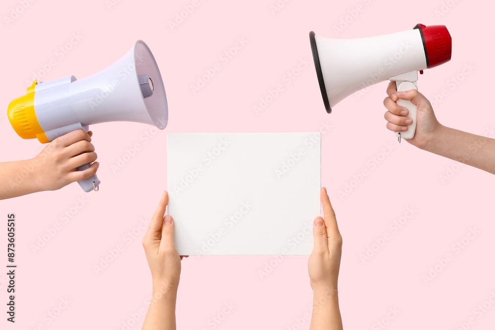 Female hands with megaphones and blank poster on pink background