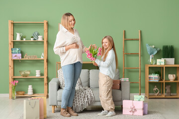 Canvas Print - Beautiful young woman and her cute little daughter with bouquet of tulips in living room