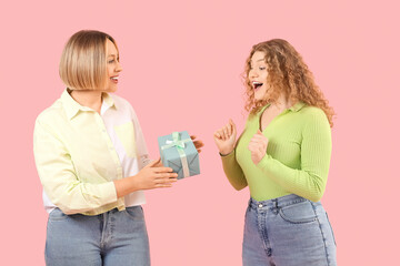 Poster - Beautiful happy women in stylish jeans with gift box on pink background