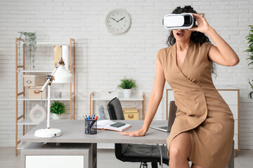 Wall Mural - Young African-American businesswoman in VR glasses in office