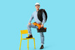 © Pixel-Shot - Young male electrician with tool box and flexible conduit tube on blue background