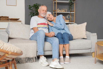 Wall Mural - Mature woman after chemotherapy with her husband sitting on sofa at home