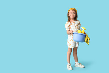 Poster - Cute little happy girl with basin of different cleaning supplies on blue background