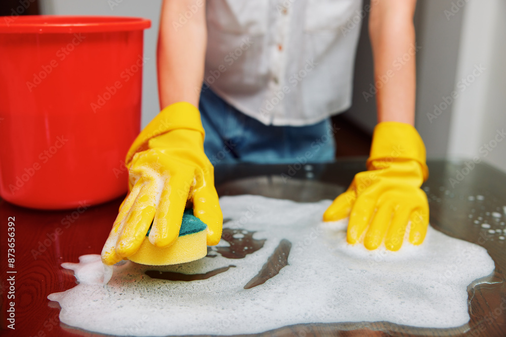 Woman in rubber gloves cleaning table with sponge and bucket of soapy ...