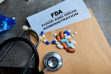 Red Handle Rubber Stamper and FDA - Food And Drug Administration text above brown envelope isolated on wooden background