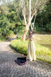 © Masakazu Tokashiki - Young Chinese Malaysian woman in her 20s playing violin near a fountain pond in a large park in Bukit Jalik, Malaysia, wearing a yellow dress.
