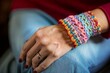 © LIUDMYLA - Close-up of Hand Wearing Colorful Crochet Bracelet and Ring on Blue Jeans