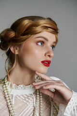 Wall Mural - A young woman with red lipstick and a pearl necklace gazes thoughtfully into the distance.