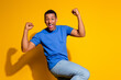 © deagreez - Photo portrait of attractive young man winning raise fists dressed stylish blue clothes isolated on yellow color background