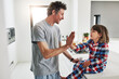 © ReeseArcurs/peopleimages.com - Boy, high five and dad in kitchen of home, learning and ASL for deaf child. Hand gesture, teaching and morning with pyjamas and son with hearing disability, celebration and education with happy man