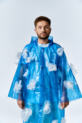 Wall Mural - A man stands in a blue plastic raincoat decorated with plastic bags.