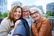 © CarlosBarquero - Selfie portrait of joyful three only mature women Caucasian friends posing happy photo standing in city. Older grey hair tourists female people looking smiling at camera together on holiday outdoors