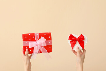 Wall Mural - Female hands with gift boxes on beige background. Valentine's Day celebration