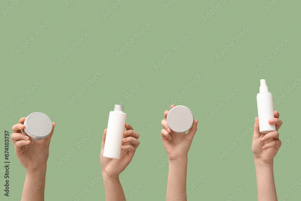 Women holding different cosmetic products on green background