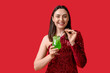 © Pixel-Shot - Happy young woman with glass of tasty cocktail on red background