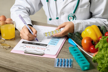 Canvas Print - Young female nutritionist with vitamins and healthy food writing diet plan in office, closeup