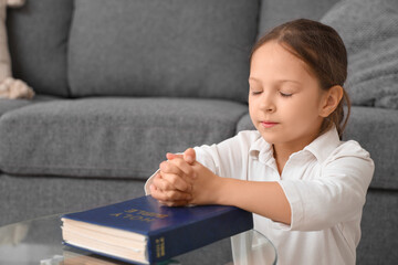 Wall Mural - Cute little girl with Bible praying at home