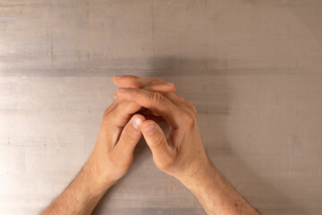 Poster - Two hands resting on a table their fingers intertwined