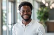 © CogniLens - Portrait of a grinning afro-american man in his 20s wearing a breathable golf polo isolated in sophisticated corporate office background