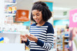 © peopleimages.com - Smile, black woman and shopping for pills in pharmacy, healthcare and prescription refill for allergy or sinus. Girl, retail and drug store for decision of pharmaceutical medication and wellness.