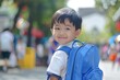 © AiHRG Design - A young boy with a bright smile looks back at the camera, ready to start a new school year in Asia.