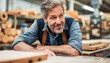 © ЮРИЙ ПОЗДНИКОВ - At a manufacturing plant, a man looks cheerful as he leans on a sturdy hardwood table