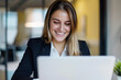 © Studio Zenith - jeune femme au travail assise devant sont ordinateur concentrée et souriante