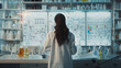 © Kowit - A woman in a lab coat is standing in front of a whiteboard with a diagram on it