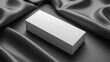 © ZethX - Minimalistic white rectangular box on luxurious black satin fabric, ideal for product presentation or elegant display concepts.