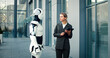 © ihorvsn - Businesswoman holding documents, stands with robot near business center. Woman looks at artificial intelligence machine that helps doing business report. Firm's future success depends on innovations.