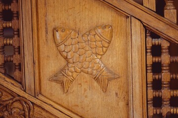 Close-up of an intricate wooden carving of two fish on a staircase railing