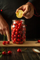 Wall Mural - A chef adds lemon to a jar of cherries before canning. The concept of making a delicious compote from sweet cherries. Advertising space