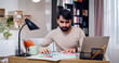 © ihorvsn - Close up portrait of Arabian male sitting at table draws diagrams on papers. Bearded face man works on new project at home.