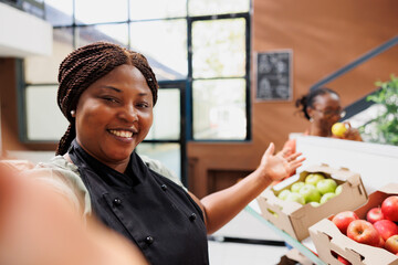 Canvas Print - Black woman promotes eco-friendly products, inspiring online audiences to buy sustainable groceries for a healthy and trendy life. Female vendor taking video of bio food store for social media.