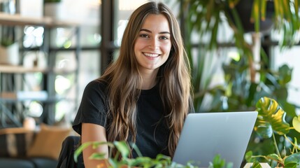 Poster - Smiling young woman using laptop in modern office. Casual business attire. Natural lighting and indoor plants add greenery to workspace. Professional and stylish. Perfect for work and study themes. AI