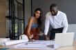 © Wavebreak Media - Collaborating on project, colleagues reviewing blueprints and using tablet in office