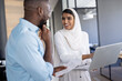 © Wavebreak Media - Discussing work, colleagues using laptop and documents in modern office setting