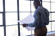 © Wavebreak Media - Reviewing architectural blueprints, businessman standing by large windows in office, copy space