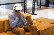 © Wavebreak Media - Using VR headset, man sitting on couch and holding tablet in office, copy space