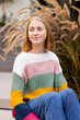© Wavebreak Media - Smiling woman in colorful sweater sitting outdoors, enjoying leisure time